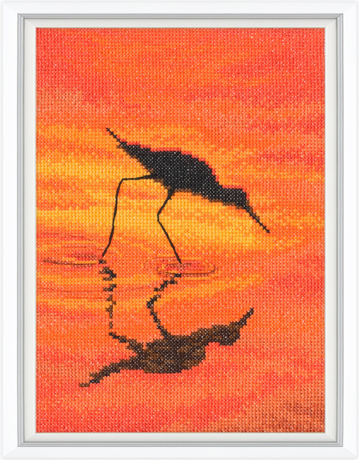 Cross-stitched artwork of a crane silhouette against an orange sunset background